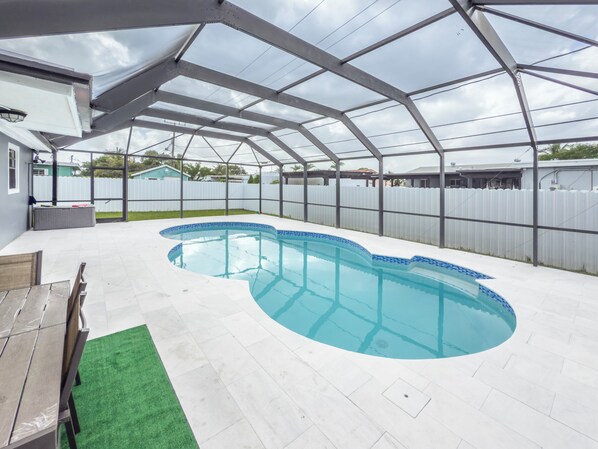 A covered swimming pool with a curved design, surrounded by a white fence and a pergola structure. - Beautiful 4-bedroom house in Heart of  Miami Gardens with POOL, AC and WiFi (Miami Gardens)