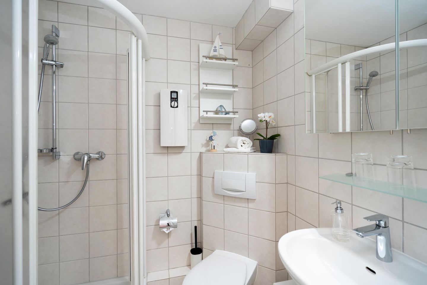 A modern bathroom with a shower, toilet, sink, and a mirror.