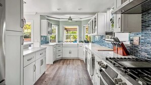 A modern kitchen with white cabinets, a large window, and a blue-tiled backsplash. - Serene hillside oasis with pool, spa, & BBQ - 20 min to beach. 31-night minimum. (Oceanside)