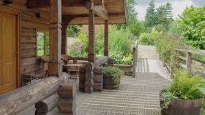 A log cabin with a wooden porch, outdoor seating, and a garden area. - Pwll Cabin, Holiday Home Marros, Sleeps 2, 1 bedrooms,  bathrooms (Carmarthen)