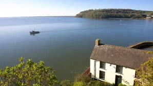 A house by a calm lake with a boat in the distance. - Pwll Cabin, Holiday Home Marros, Sleeps 2, 1 bedrooms,  bathrooms (Carmarthen)