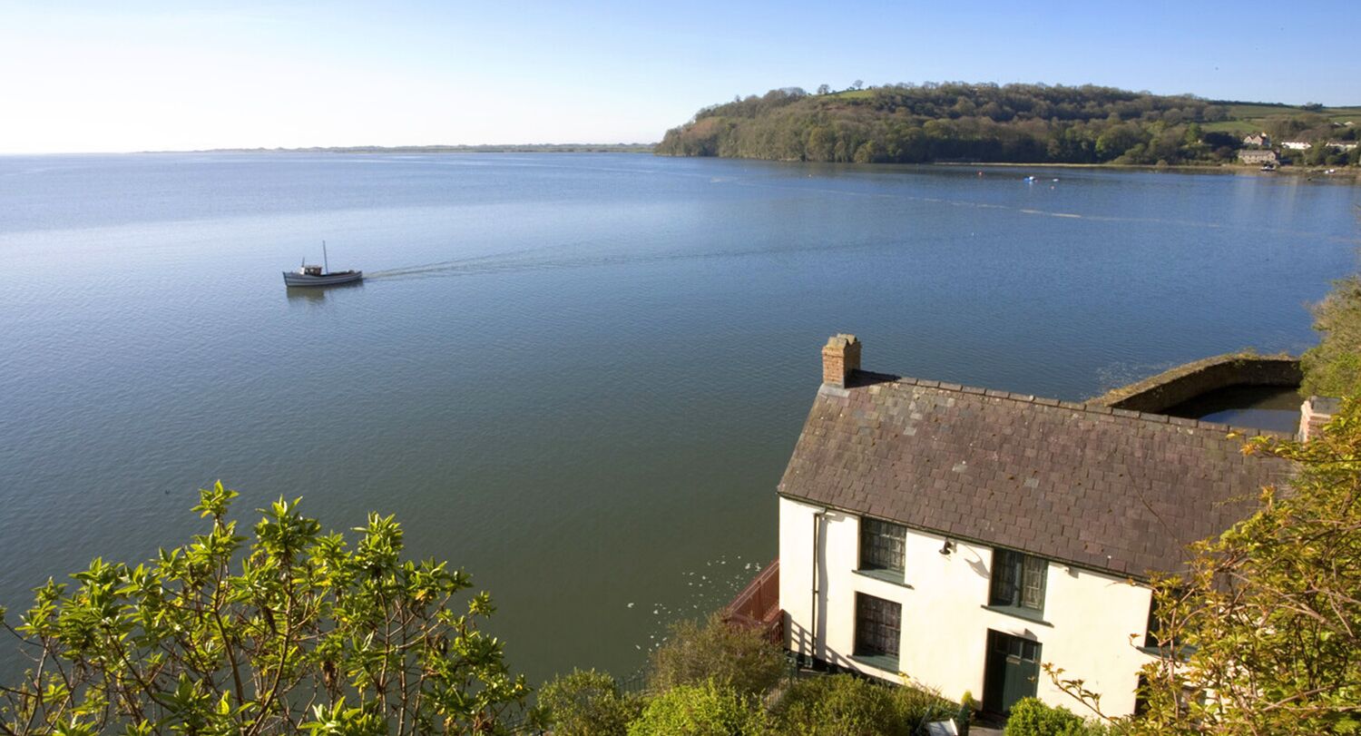 A house by a calm lake with a boat in the distance.