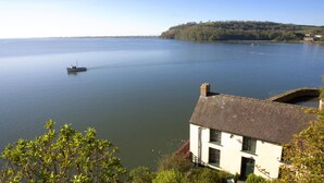 A house by a calm lake with a boat in the distance. - Pwll Cottage, Holiday Cottage Marros, Sleeps 6, 3 bedrooms,  bathrooms (Carmarthen)