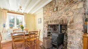 A cozy room with a stone fireplace, wooden furniture, and a window with curtains. - Pwll Cottage, Holiday Cottage Marros, Sleeps 6, 3 bedrooms,  bathrooms (Carmarthen)