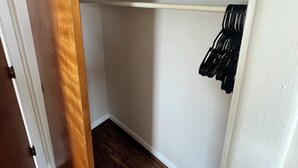 Un dressing accessible sans porte, doté d’un plancher en bois, de murs blancs et d’un plafond blanc.