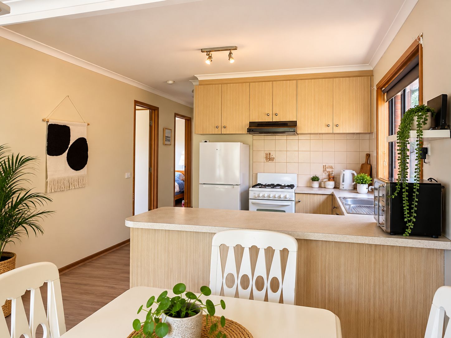 A compact kitchen with wooden cabinets, a white countertop, a refrigerator, a stove, and a sink.