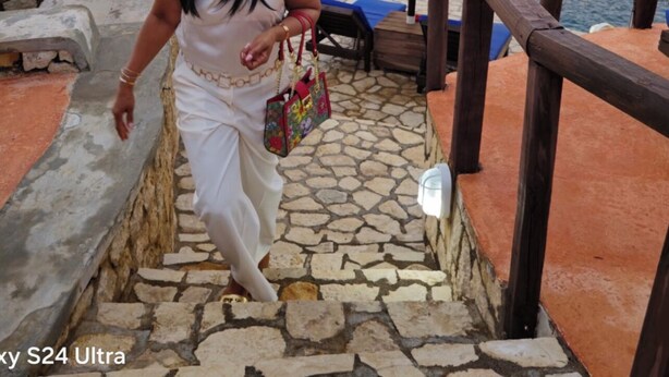 A person descending a stone staircase with a view of the sea and a thatched structure in the background. - Charming 3-bedroom house with AC and WiFi in Negril (Negril)