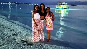 A beach scene with clear water, a boat, and three people standing on the shore. - Charming 3-bedroom house with AC and WiFi in Negril (Negril)