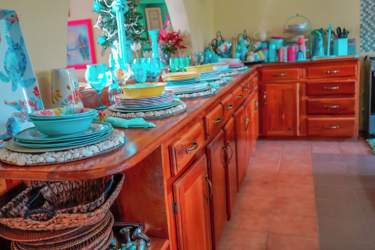 A kitchen with a long countertop, wooden cabinets, and various kitchenware.