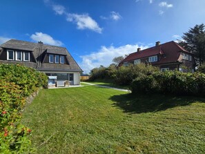A residential area with two houses, a well-maintained lawn, and a clear sky.