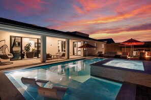 A modern outdoor pool area with a sunset view, lounge chairs, and a covered seating area. - Lake Havasu 4BR Pool, Game Room, RV Garage & Firepit (Lake Havasu City)