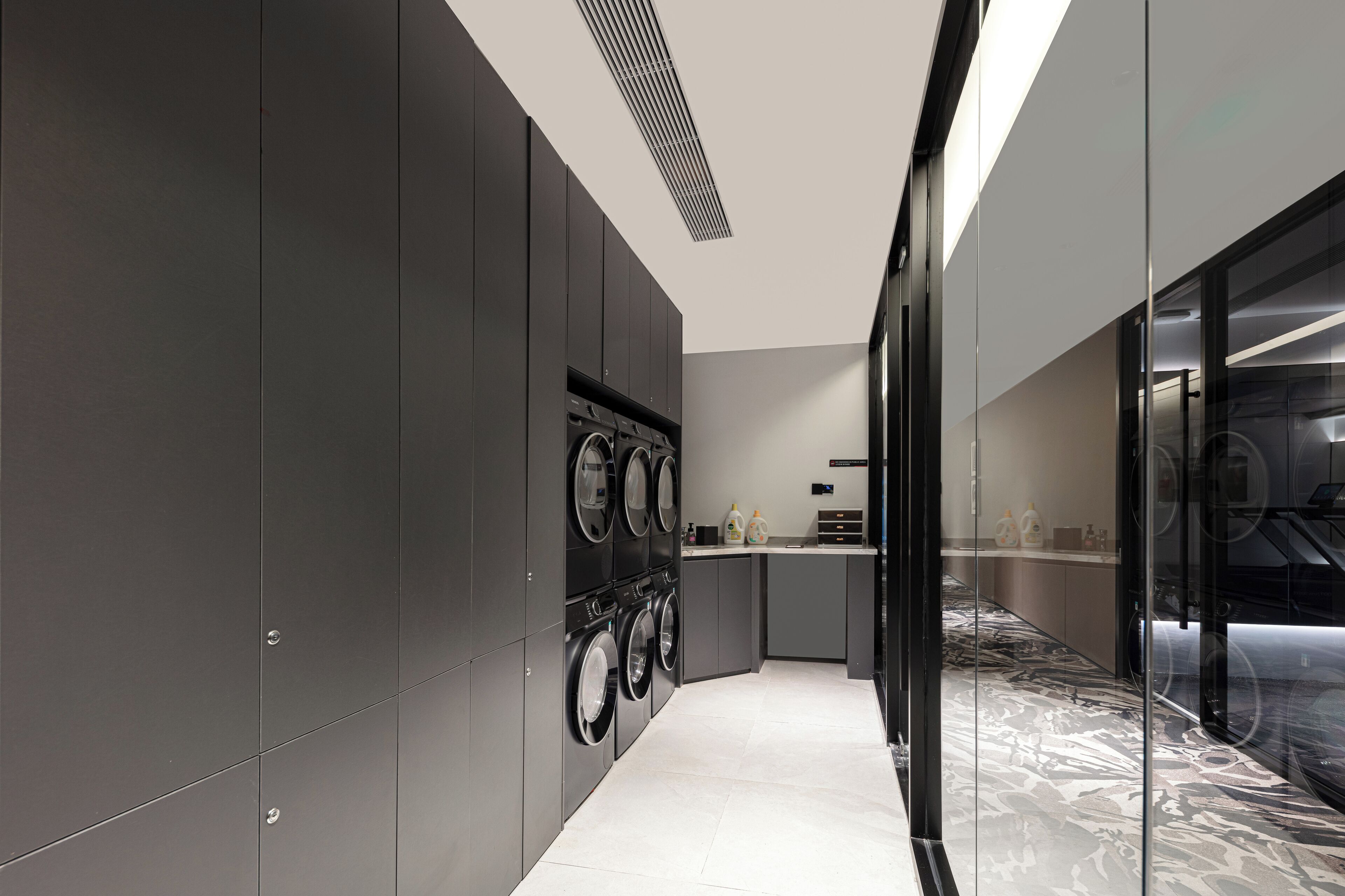 A modern kitchen with built-in appliances, a marble backsplash, and a glass partition.