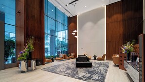 Un vestíbulo moderno con amplios ventanales de vidrio, paneles de madera y un mostrador de recepción con un jarrón de flores.