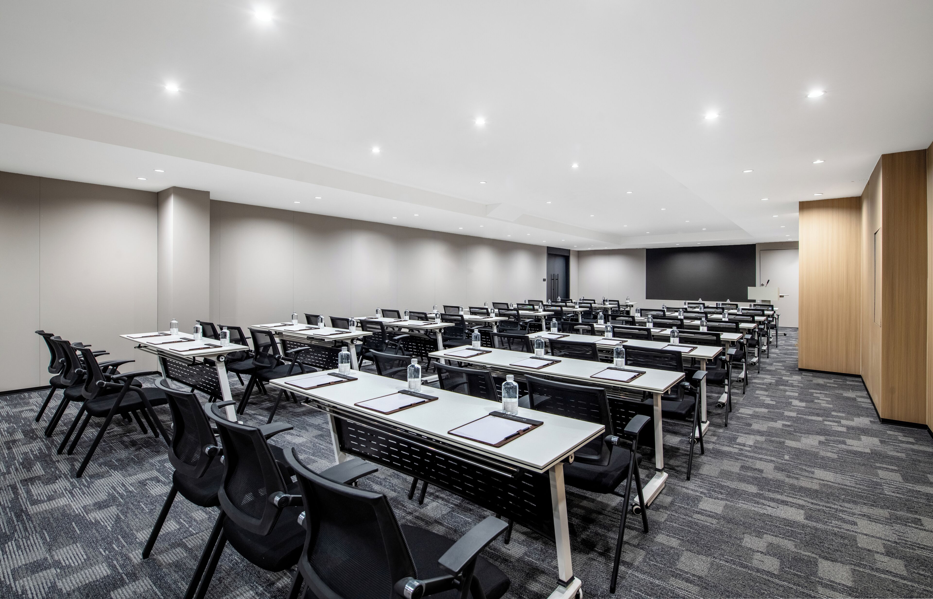 Una sala de conferències amb diverses taules i cadires, equipada amb ampolles d'aigua i fulls de paper.