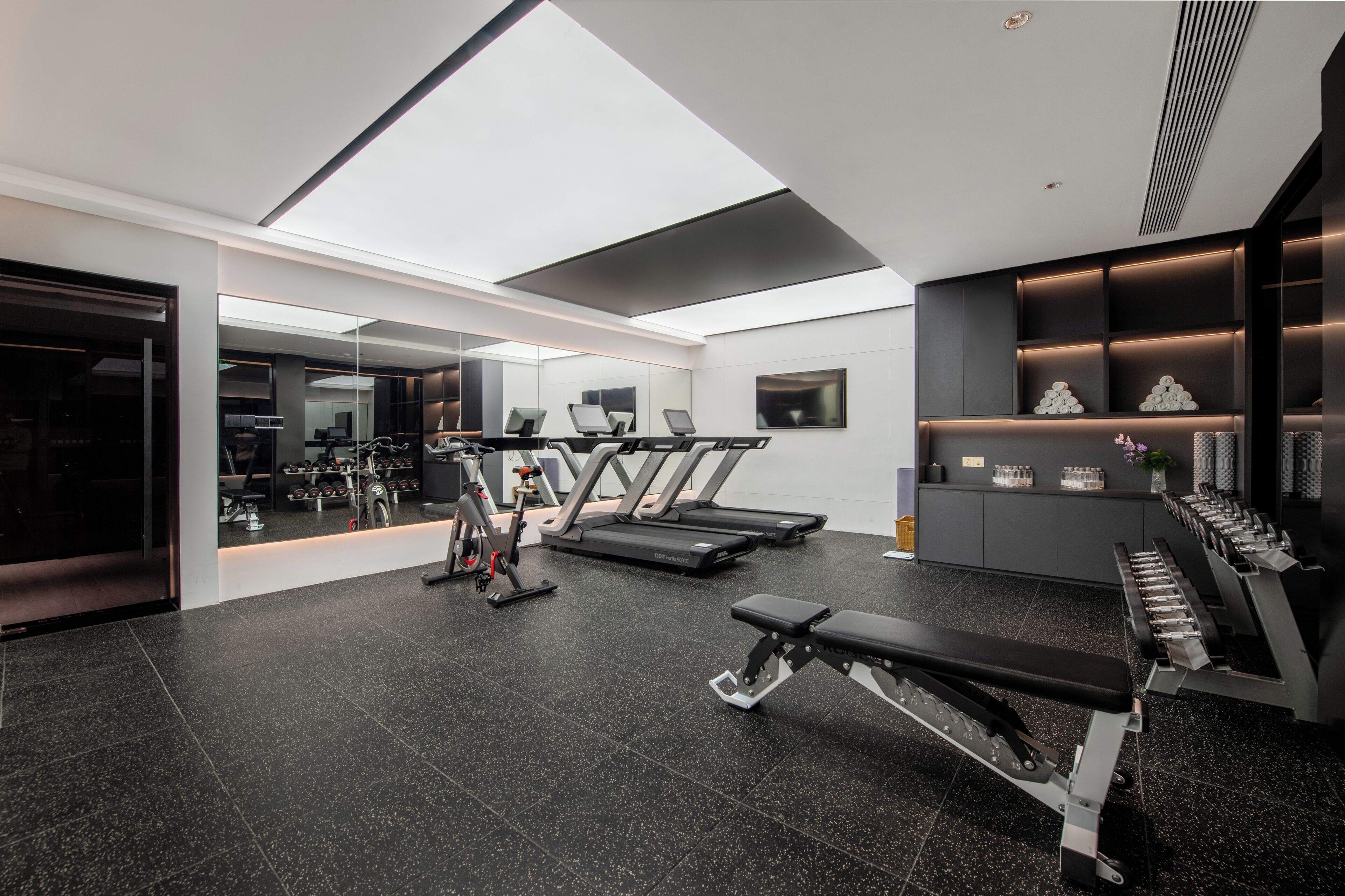 A modern gym with treadmills, a rowing machine, and a bench press.