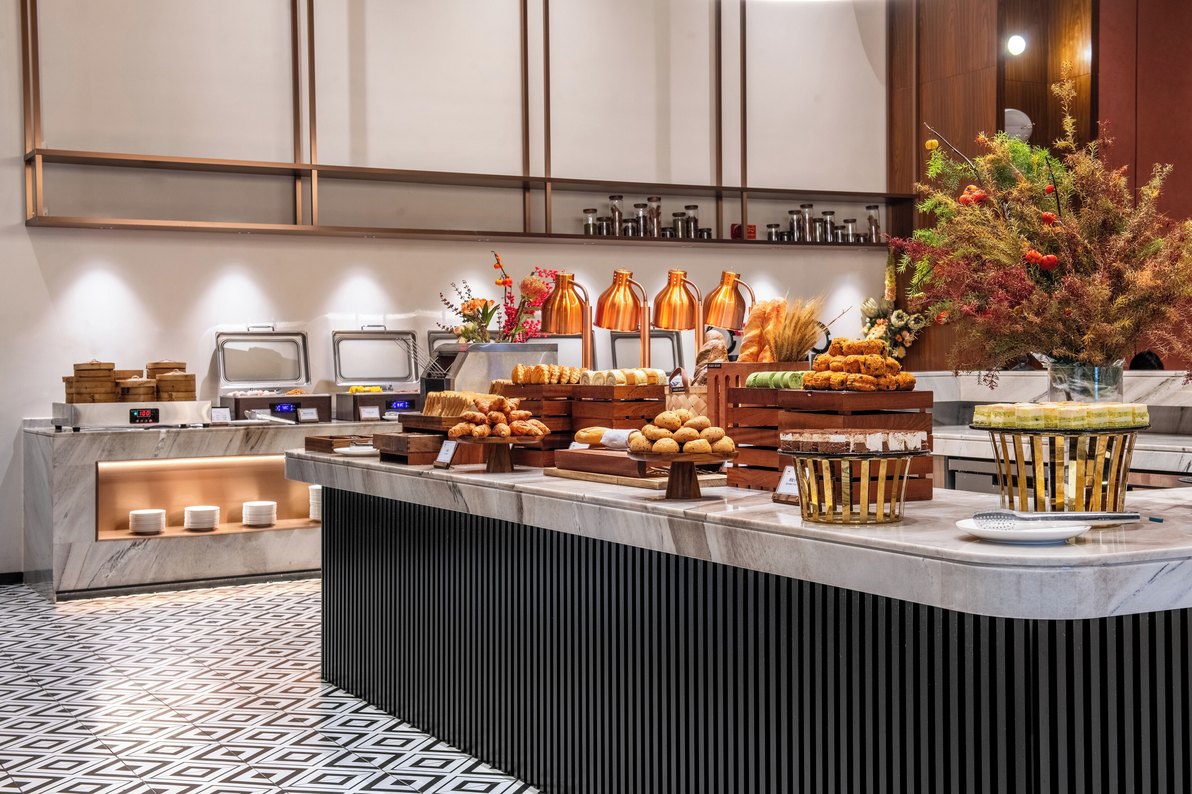 A buffet area with various food items, a digital clock, and a decorative plant.