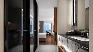 Un baño de hotel moderno con un lavamanos de mármol, un secador de pelo y un espejo.