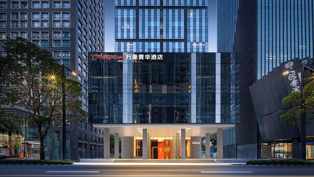 Un hotel moderno con fachada de vidrio, una entrada destacada y un exterior bien iluminado.