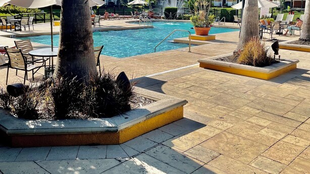 Ein Poolbereich mit Liegestühlen, Sonnenschirmen und einer Springbrunnen.