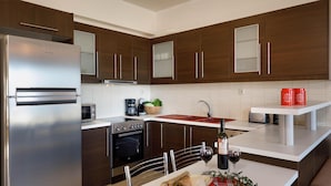 Une cuisine moderne avec des meubles en bois foncé, des appareils électroménagers en acier inoxydable et un plan de travail blanc.