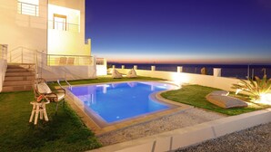 Ein moderner Poolbereich mit Blick auf das Meer im Abenddämmerung.