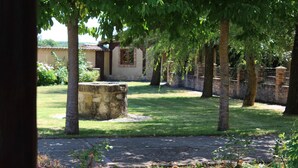 Um pátio com calçada pavimentada, construções de pedra e árvores.