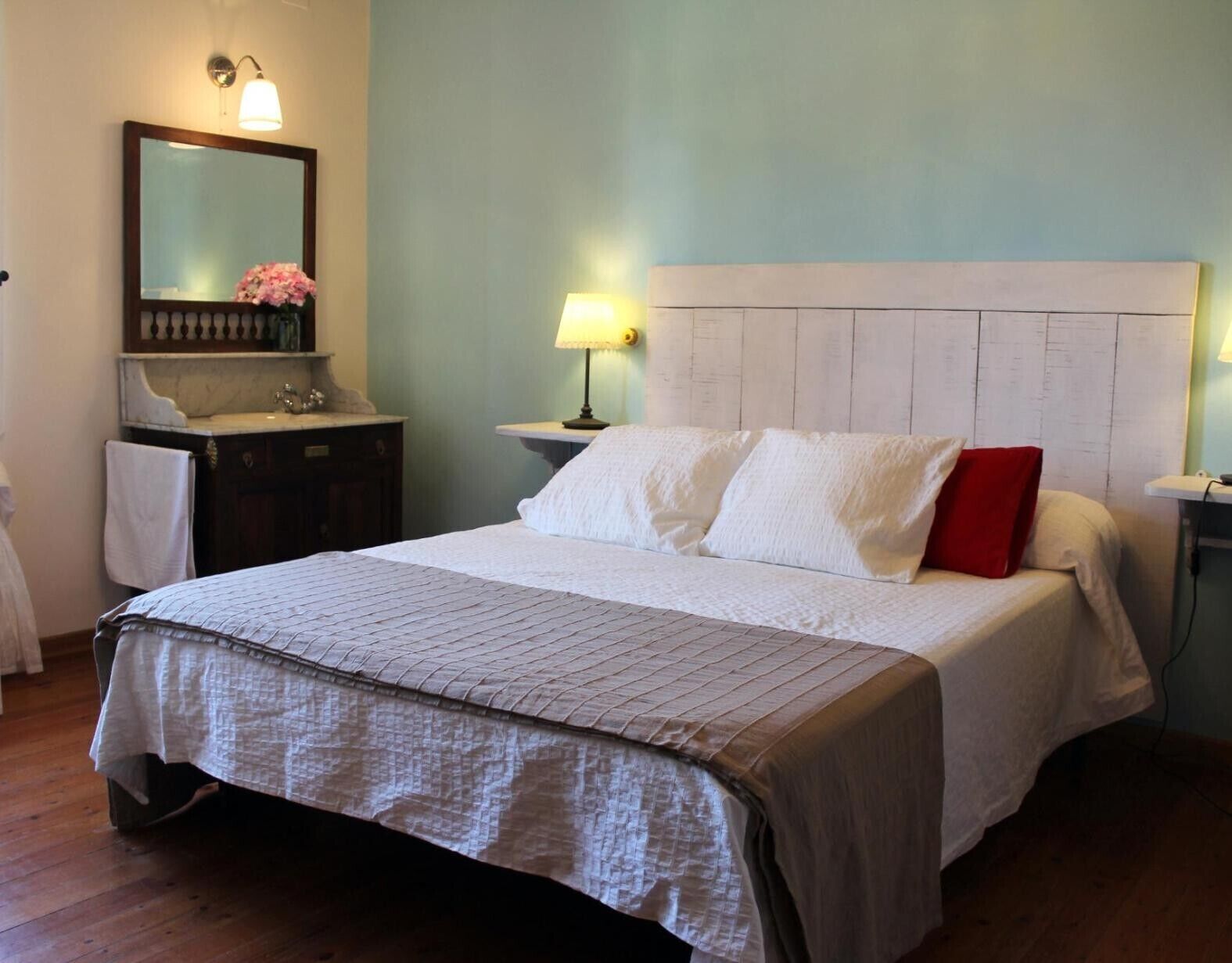 Ein ordentlich eingerichtetes Schlafzimmer mit Bett, Nachttischen, einem Spiegel und einem Beistelltisch.