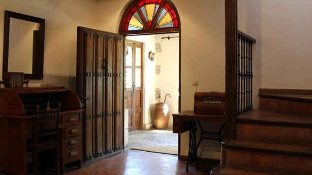 Um quarto com escrivaninha de madeira, um espelho grande, uma janela de vitrais e uma escada.