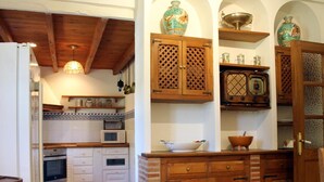 Cozinha com armários brancos, micro-ondas e prateleiras de madeira com objetos decorativos.
