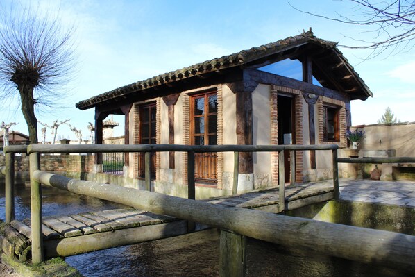 A traditional building with a wooden deck over water, featuring a brick facade and large windows.