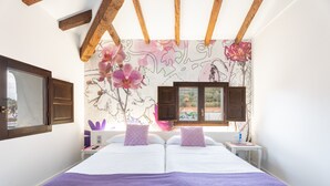 Una camera da letto con due letti, travi in legno, una finestra e un affresco al muro.