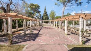 Un porticato con colonne e pavimento piastrellato, circondato da alberi.