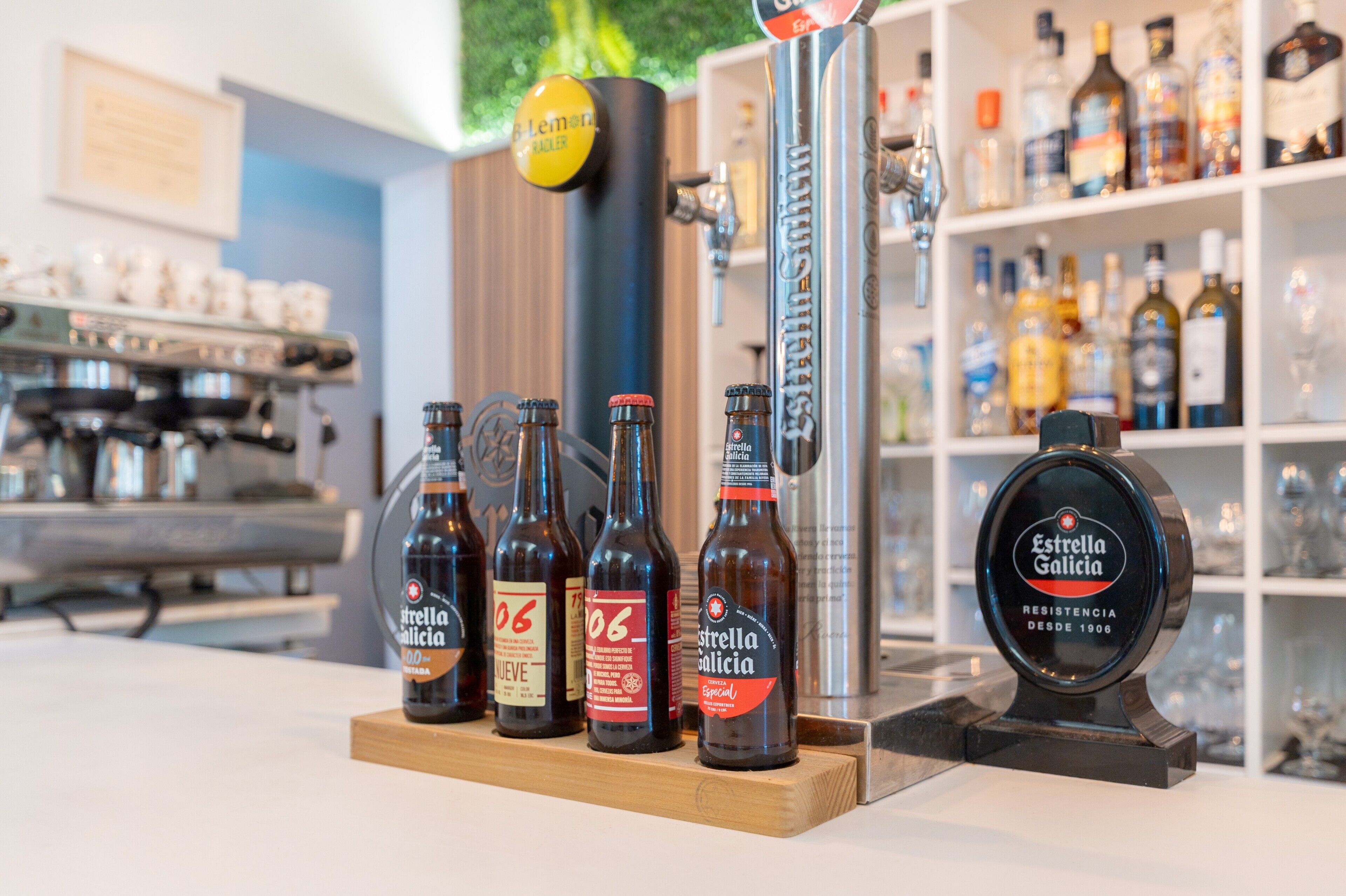 En bardisk med flaskor av Estrella Galicia, en ölkran märkt med texten ”Hemer” och en hylla med olika sorters spritflaskor.
