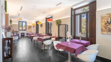 Un restaurante con varias mesas, sillas e iluminación colgante.