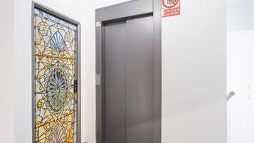 Una puerta con un diseño de vitral y una puerta de ascensor sencilla.