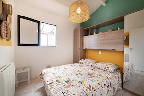 Une chambre à coucher avec un lit, un petit tabouret, un luminaire suspendu et une fenêtre.