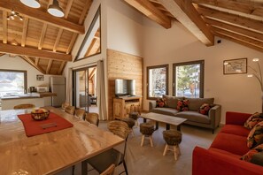 Un amplio salón con techo de madera, un sofá, un sofá rojo y una mesa de comedor con sillas.