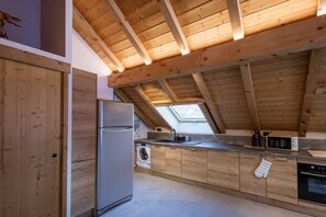 A modern kitchen with wooden beams, a stainless steel refrigerator, a washing machine, and a microwave. - Apartment 'Strato 8' with Mountain View, Balcony and Wi-Fi (Valloire)