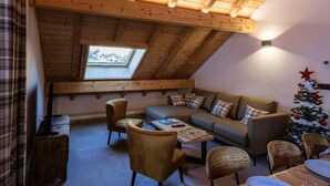 Una camera accogliente in stile loft con soffitto spiovente, un divano, sedie, un tavolino da caffè e un albero di Natale.