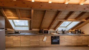 Una cucina moderna con travi in legno, lucernari e elettrodomestici a scomparsa.