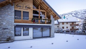Un edificio a due piani con facciata in pietra e livello superiore in legno, con insegna 'Sous la Roche Restaurant'.