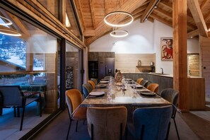 Un comedor con una mesa larga, sillas y vistas amplias por las ventanas.