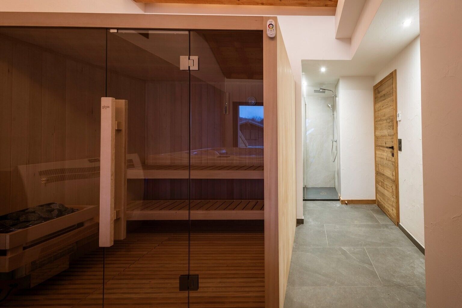 Un sauna doté de portes en verre, de bancs en bois et d’un panneau de commande.