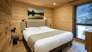 A wooden cabin bedroom with a bed, a painting of a mountain, and a window with a snowy view. - Chalet '-Spa Le Cervin' with Mountain View, Private Terrace and Wi-Fi (Valloire)