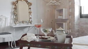 Une chambre d’hôtel avec un mur en bois, une commode blanche, un miroir, un plateau avec une théière, un verre et une assiette avec de la nourriture.