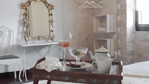 Habitación de hotel con pared de madera, cómoda blanca, espejo, bandeja con tetera, vaso y plato con comida.