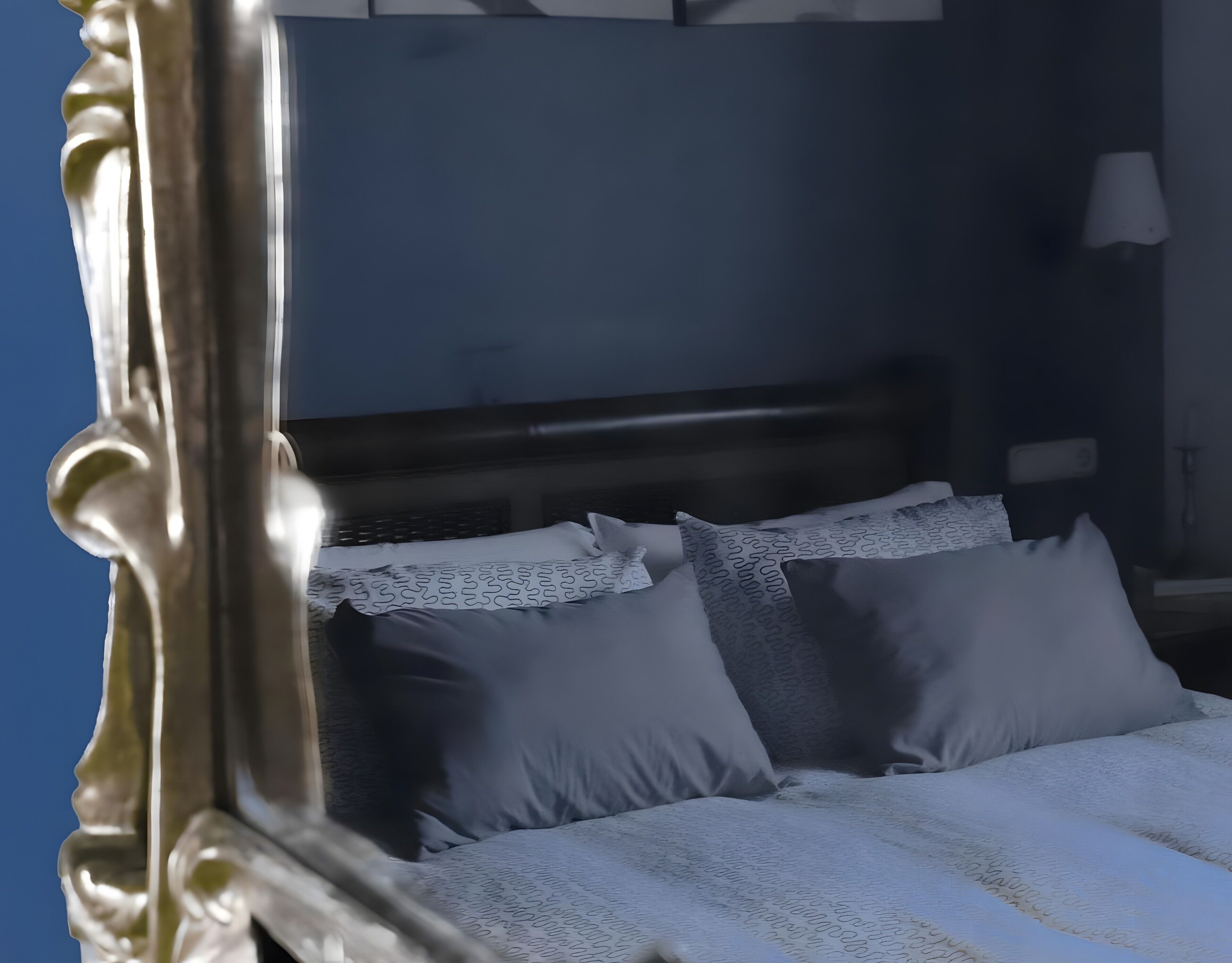 Una cama con cabecera, almohadas y una manta.