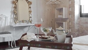 Ein Zimmer mit Schreibtisch aus Holz, einem Spiegel, einem Tablett mit Teekanne, Glas und einem Teller mit Essen.