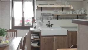 Cuina amb un rentaplat, armaris de fusta i una finestra amb cortines.