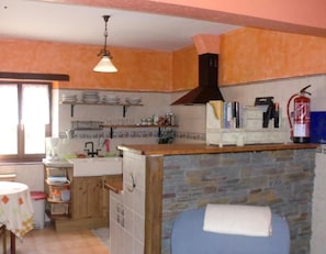 Una cocina con isla de piedra, armarios de madera y un extintor.
